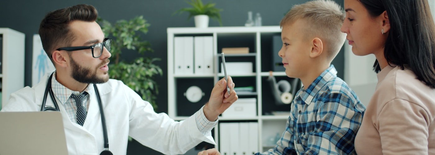 Doctor examining young child with mother present